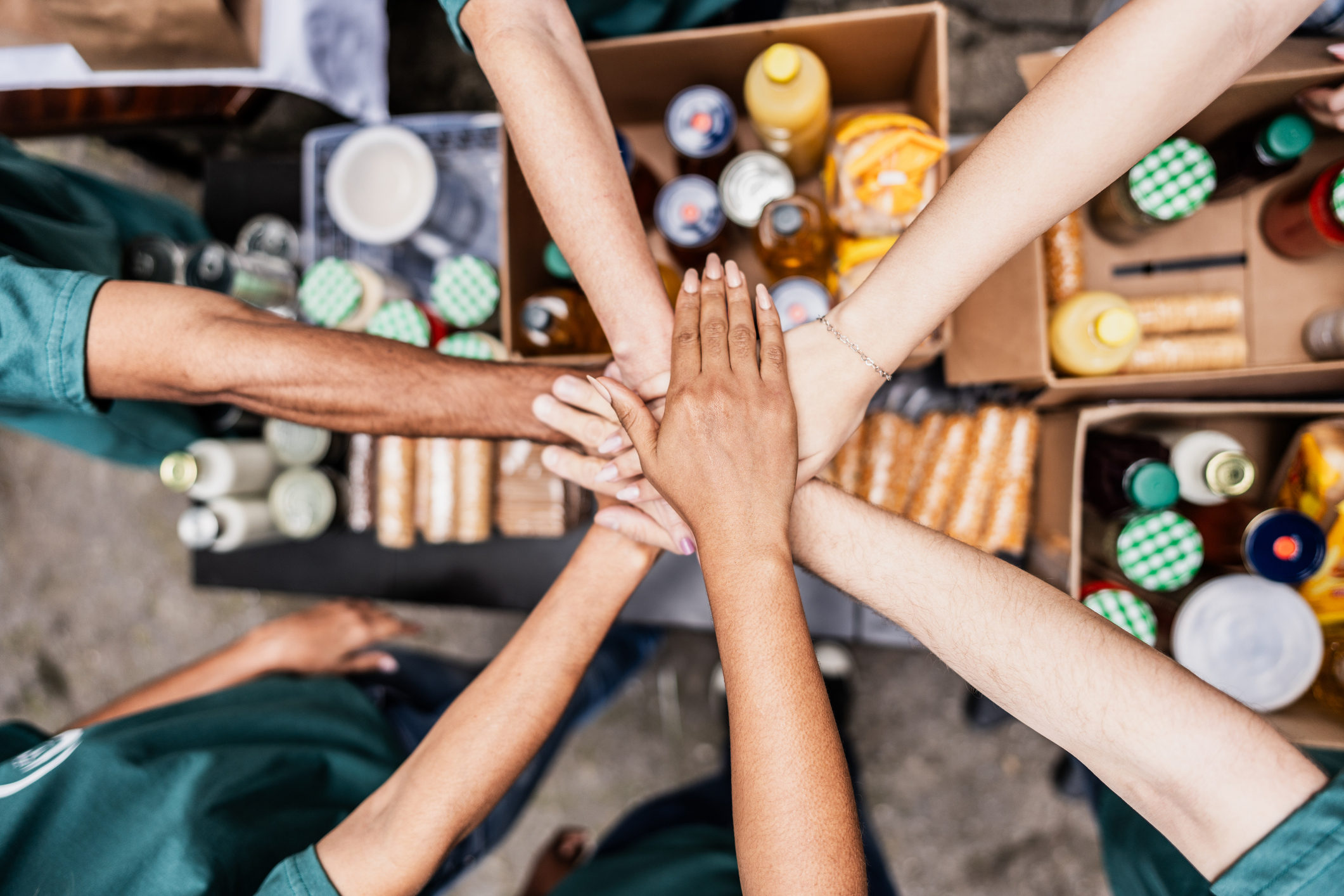 Close-up of volunteers with hands stacked during donation event outdoors